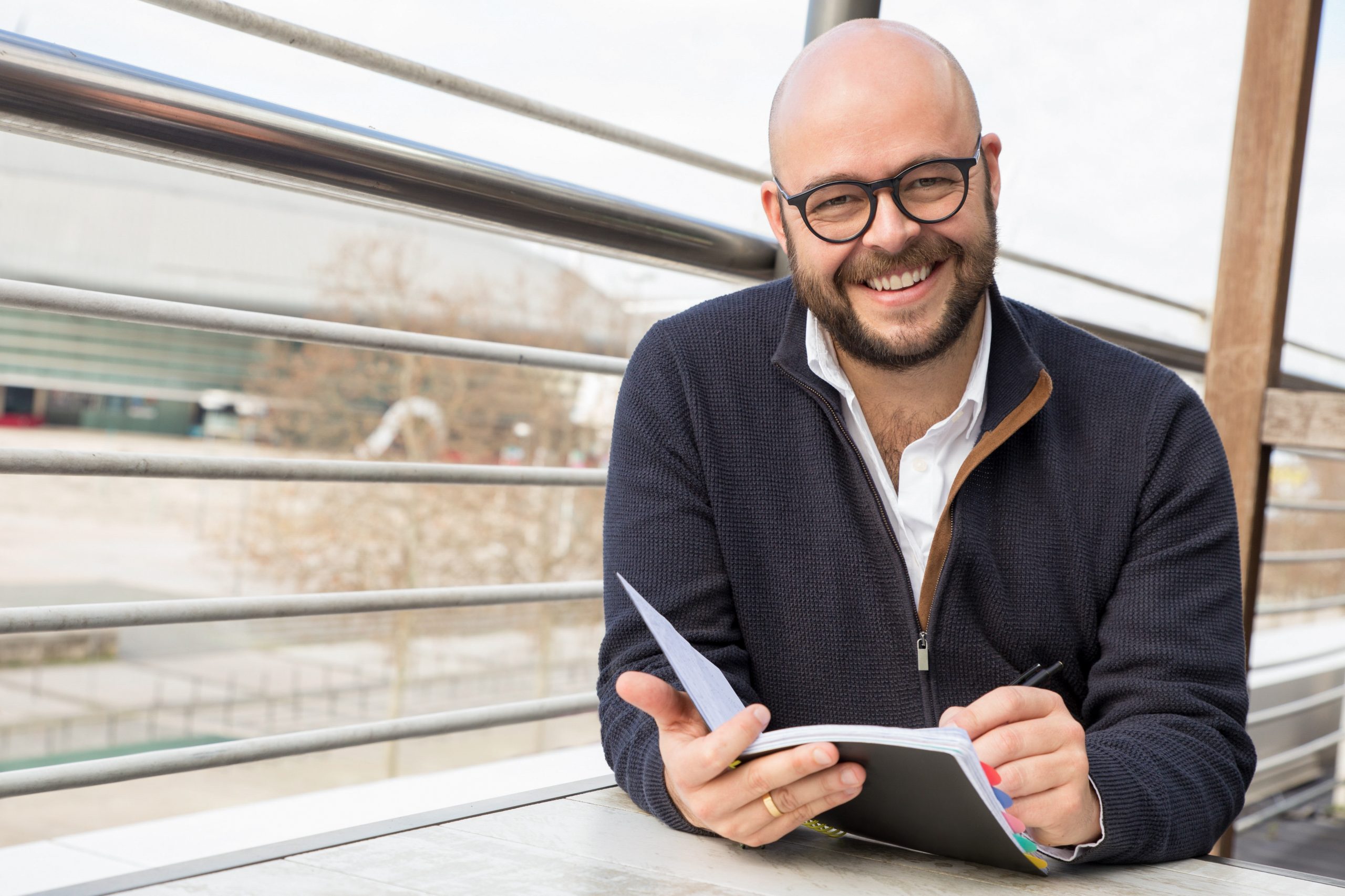 hombre de mediana edad feliz que hace notas en cafe de la calle